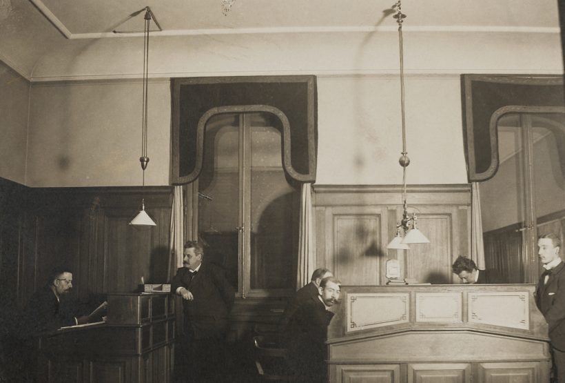 Bild av kontoret i Hallwylska palatset, från början av 1900-talet. Flera män står vid sina skrivbord.