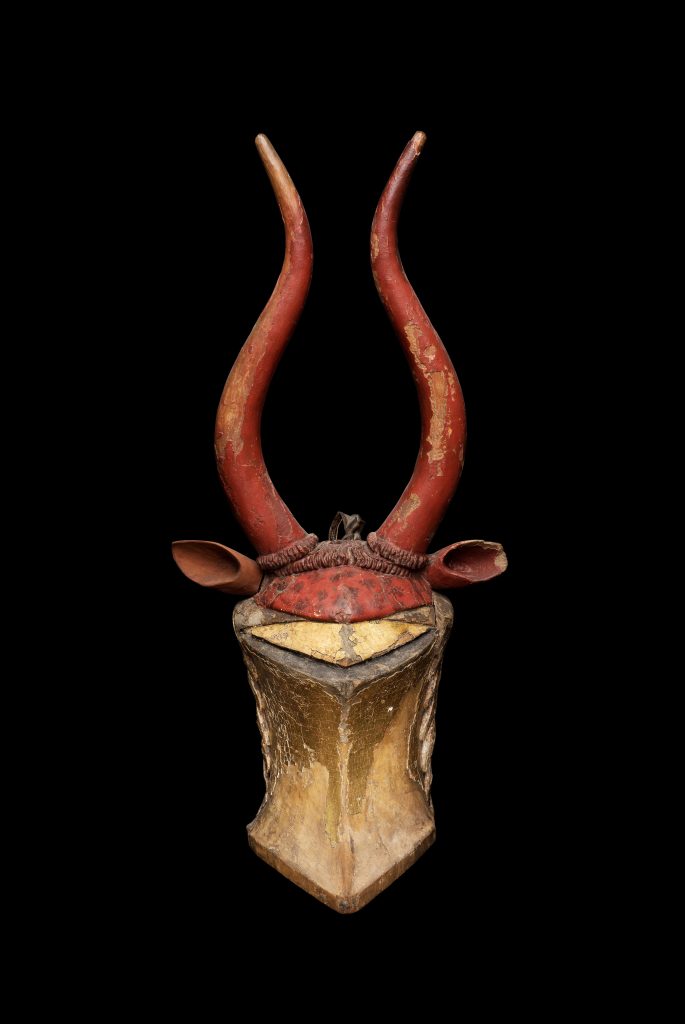 En förgylld medeltida sluten hjälm med dekorationer i form av höga horn och oxöron i rött