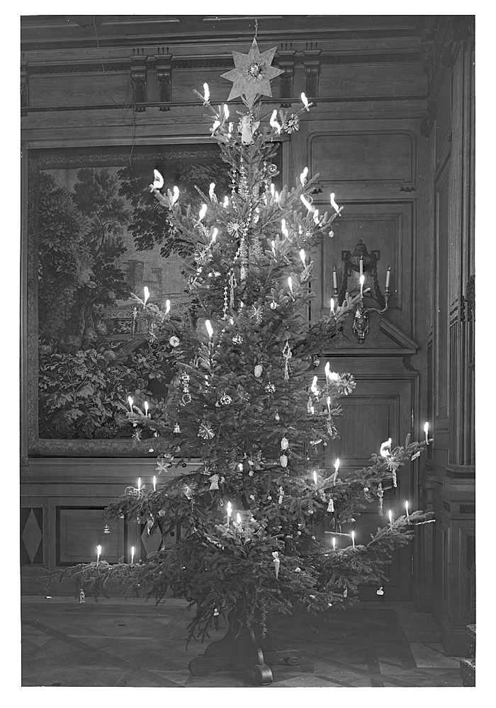 En svartvit bild på en julgran inomhus med många levande ljus