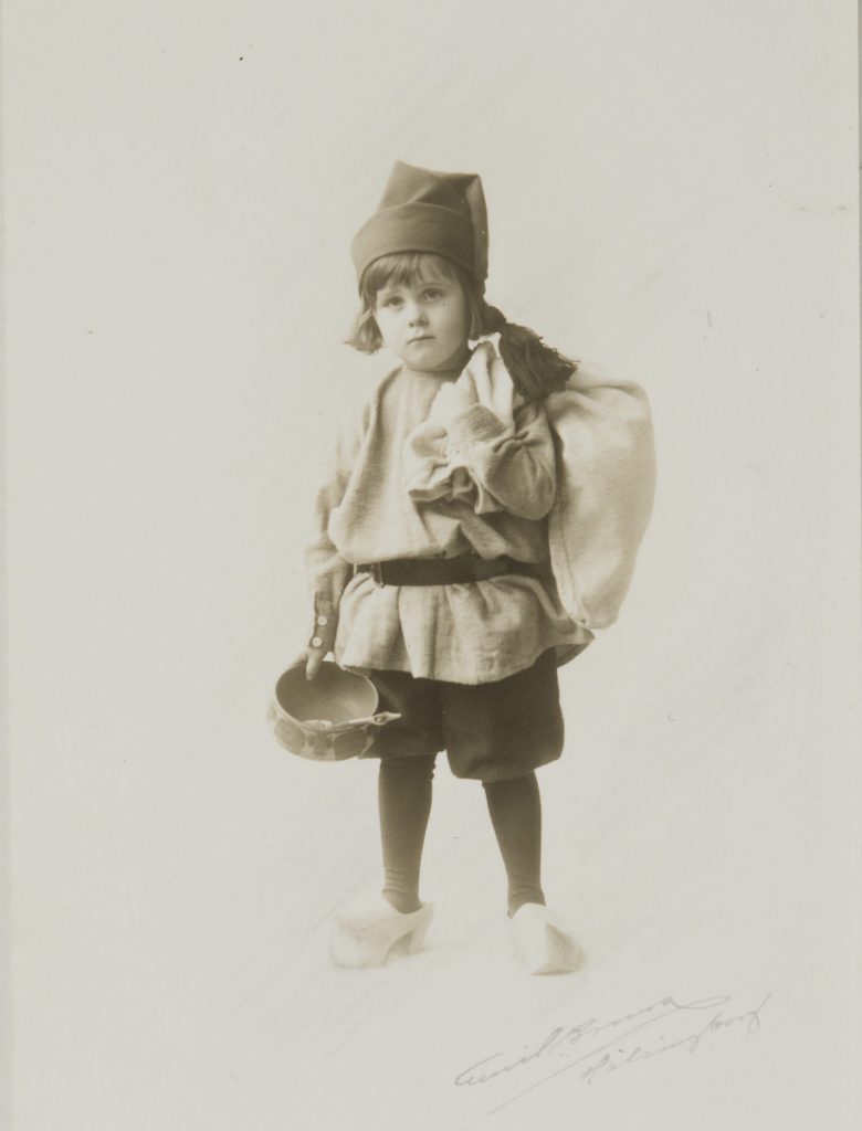 Ett svartvitt foto av ett barn klädd som tomtenisse