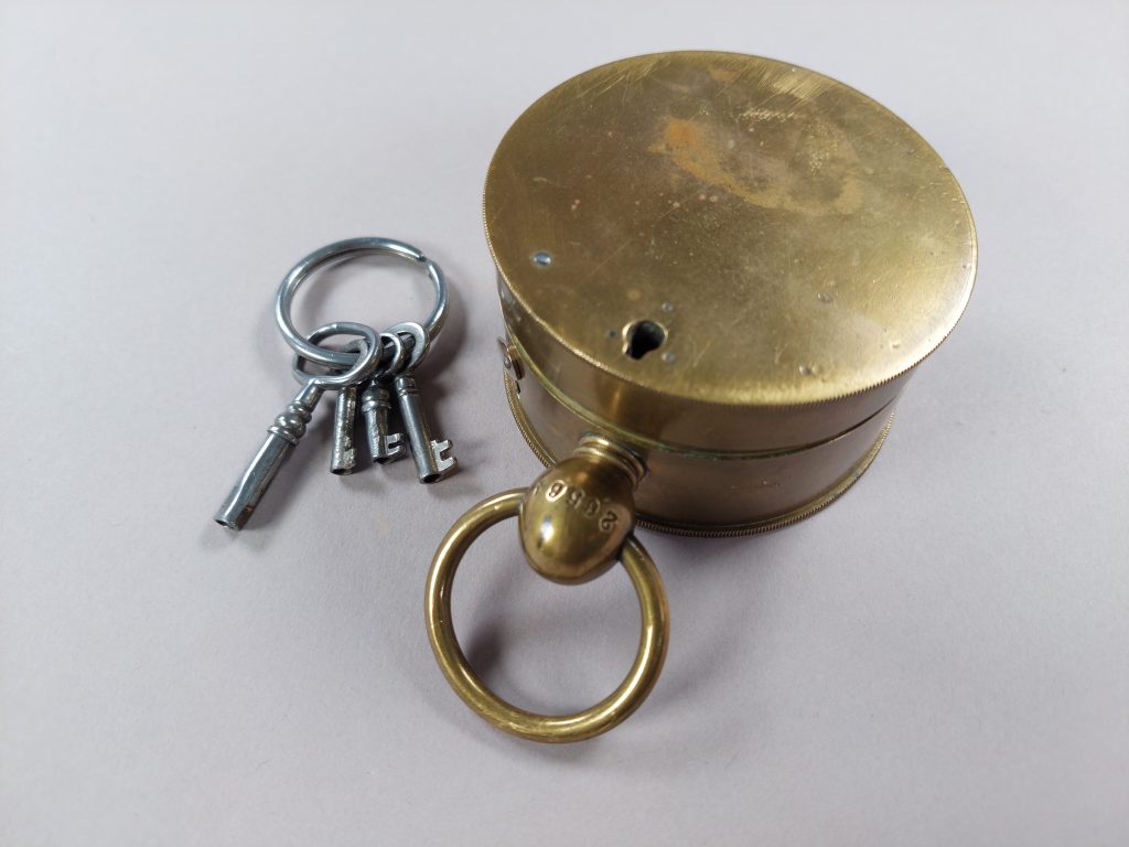 Burkformat mässingsföremål med tillhörande nycklar.