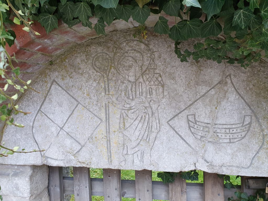 Stenrelief med kvinna och två vapensköldar.