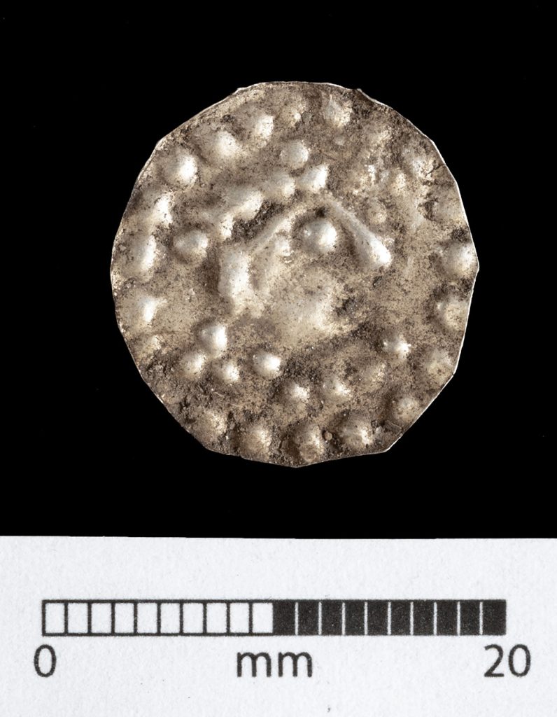 Silvermynt med ett ansikte vänt åt höger och prickar runt kanten.