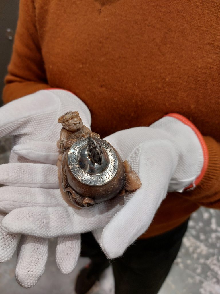 Bläckhornet sett snett uppifrån, vilandes i två handskbeklädda händer.