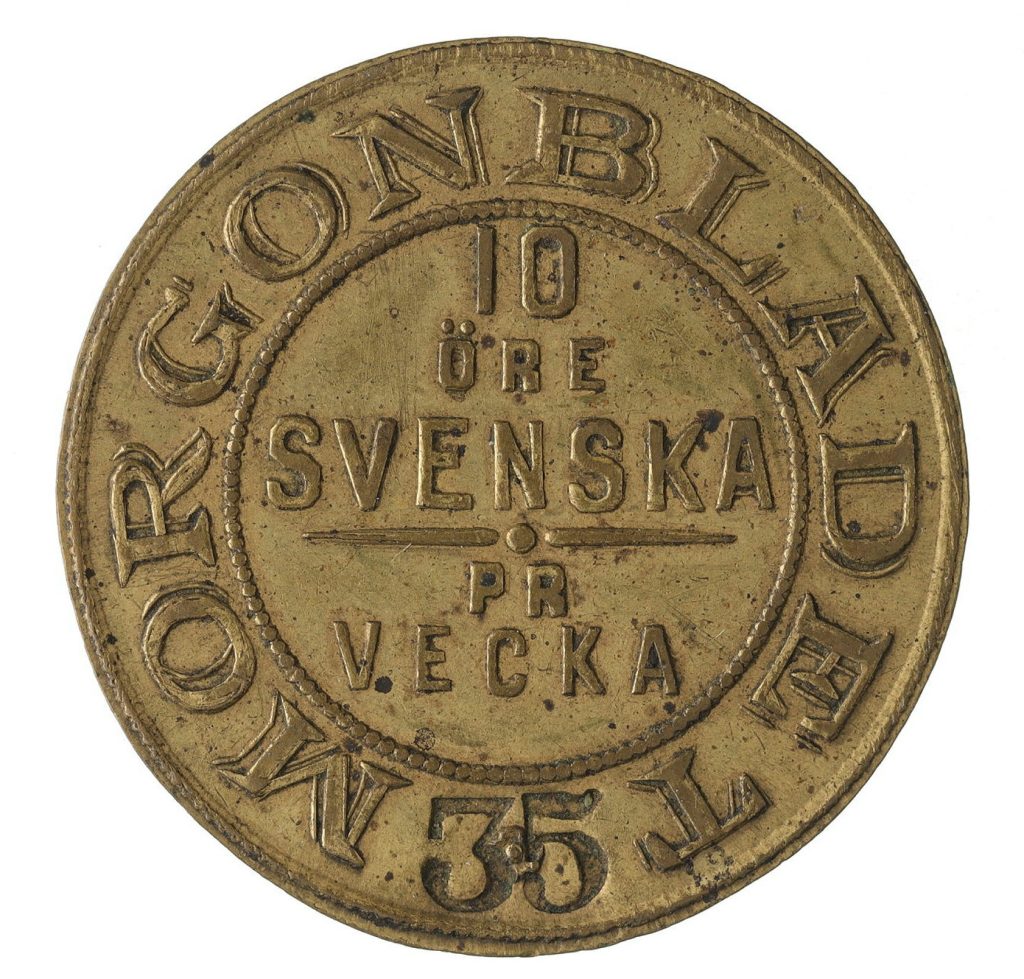 Rund pollett av gulmetall med texten Morgonbladet.