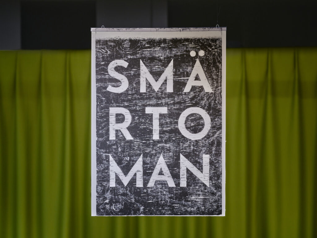 Träsnitt med texten Smärtoman.