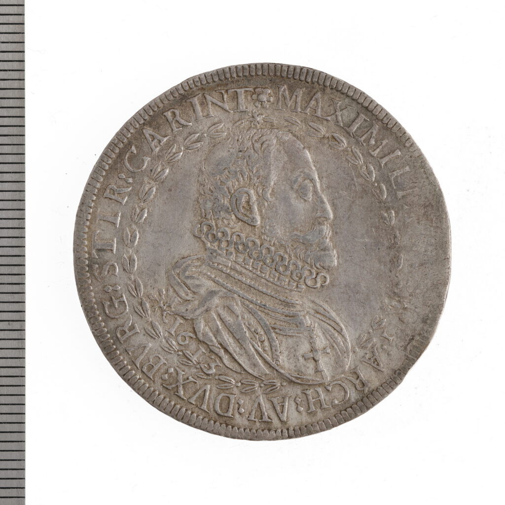 Silverfärgat mynt med porträtt av en man i profil.