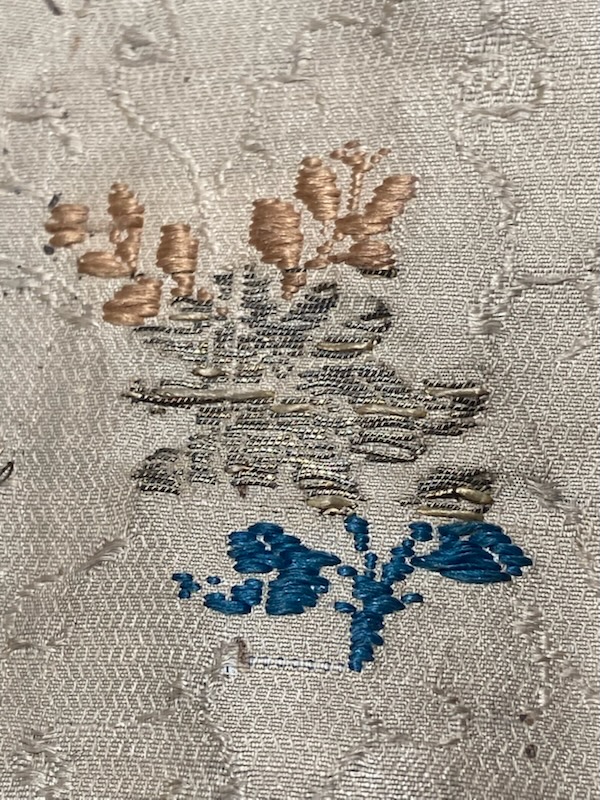 Närbild av sidentyg med broderade blombuketter.